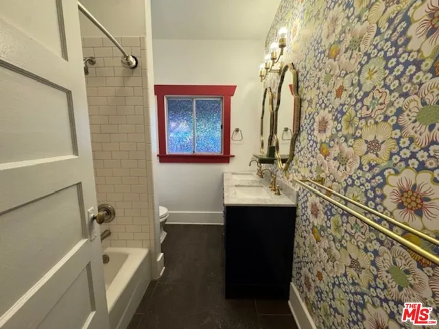 a bathroom with a sink and mirror with bathtub
