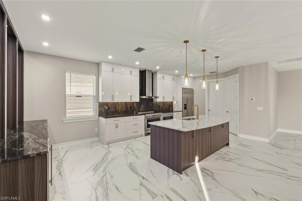 28049 Captiva Shell Loop Bonita Springs, FL 34135 - Photo 10 of 50 a room with kitchen island a sink a stove a refrigerator and cabinets