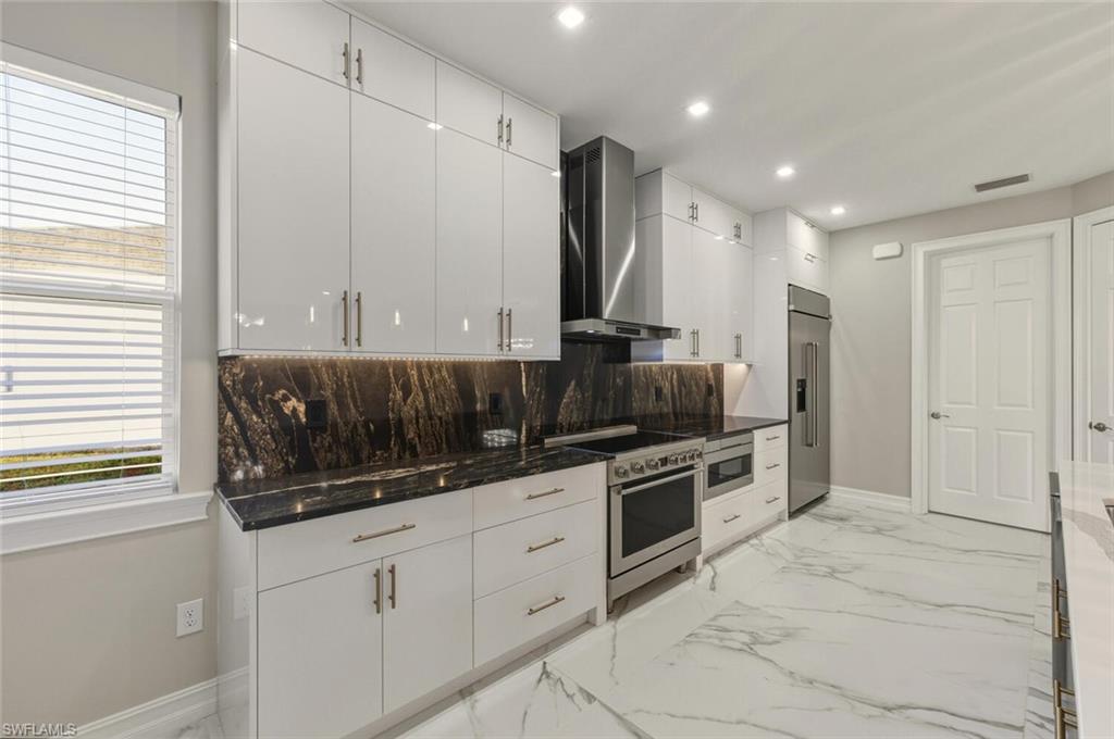 28049 Captiva Shell Loop Bonita Springs, FL 34135 - Photo 11 of 50 a kitchen with stainless steel appliances kitchen island granite countertop a stove a sink and a microwave