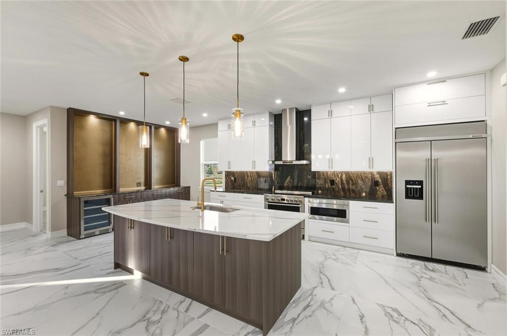 28049 Captiva Shell Loop Bonita Springs, FL 34135 - Photo 8 of 50 a large kitchen with stainless steel appliances kitchen island granite countertop a refrigerator a stove and a sink