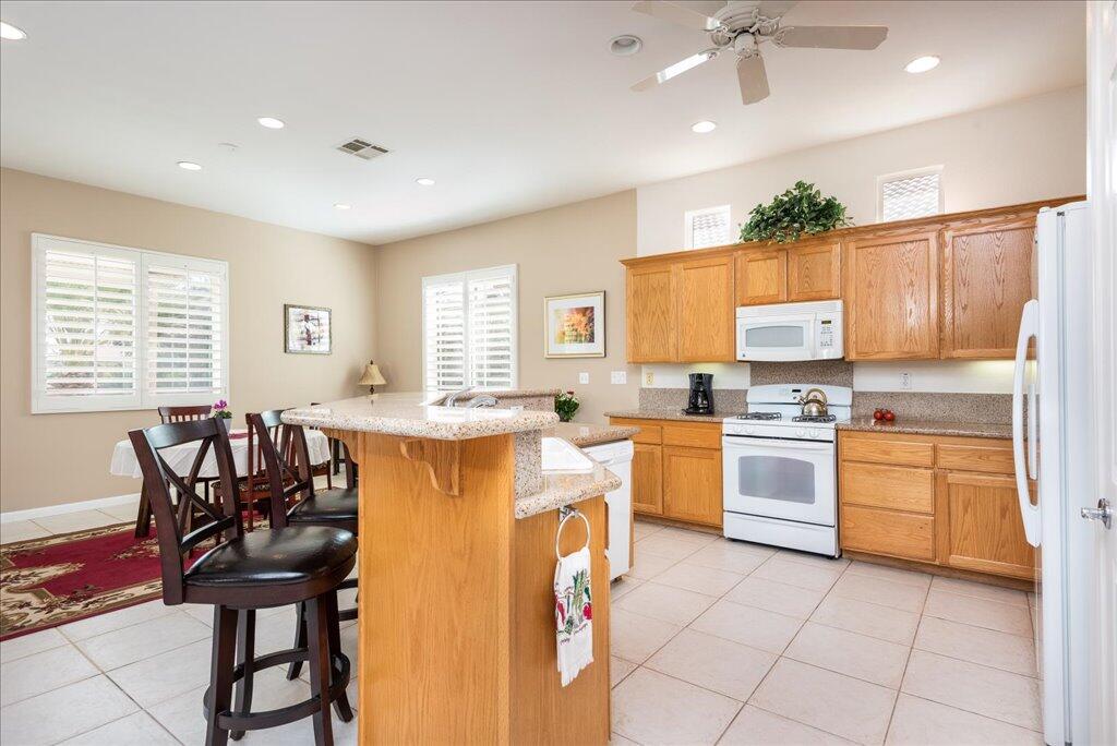 49562 Wayne Street Indio, CA 92201 - Photo 10 of 52 a kitchen with granite countertop cabinets a sink a stove a dining table and chairs
