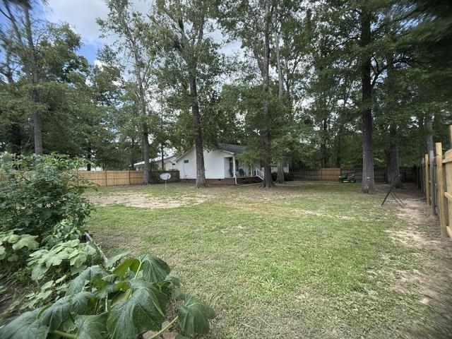 395 Austin Street Savannah, TN 38372 - Photo 24 of 32 Expansive backyard featuring a partial wood privacy fence, mature trees, and a white-sided residence in the background