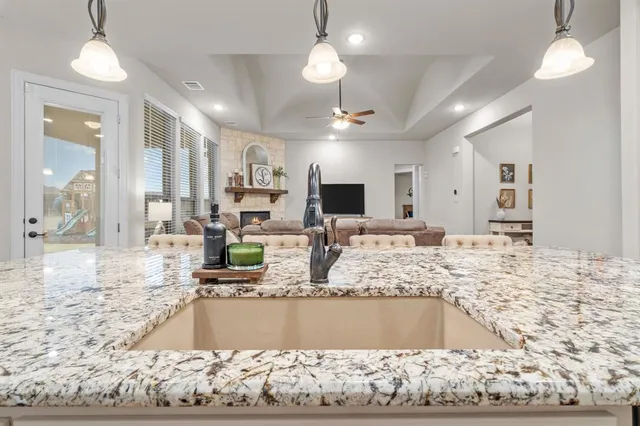 a kitchen with kitchen island granite countertop a table chairs refrigerator and microwave