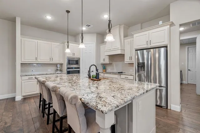 a large kitchen with granite countertop a large counter top appliances and cabinets