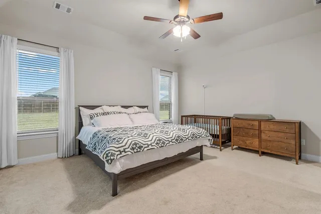 a bedroom with a bed table and a flat tv screen