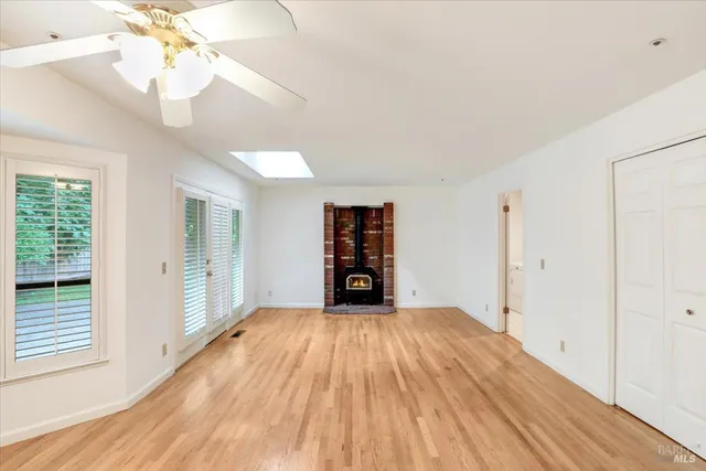 a view of an empty room with window and wooden floor