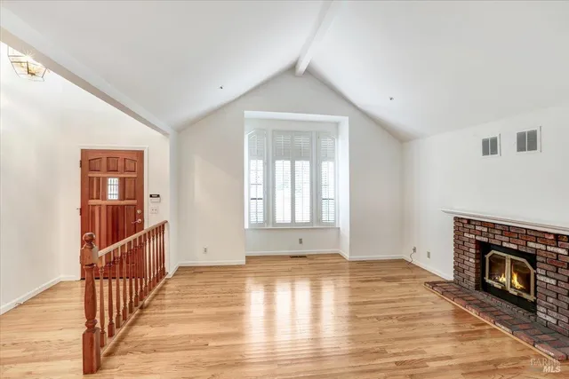 a view of empty room with wooden floor and fireplace