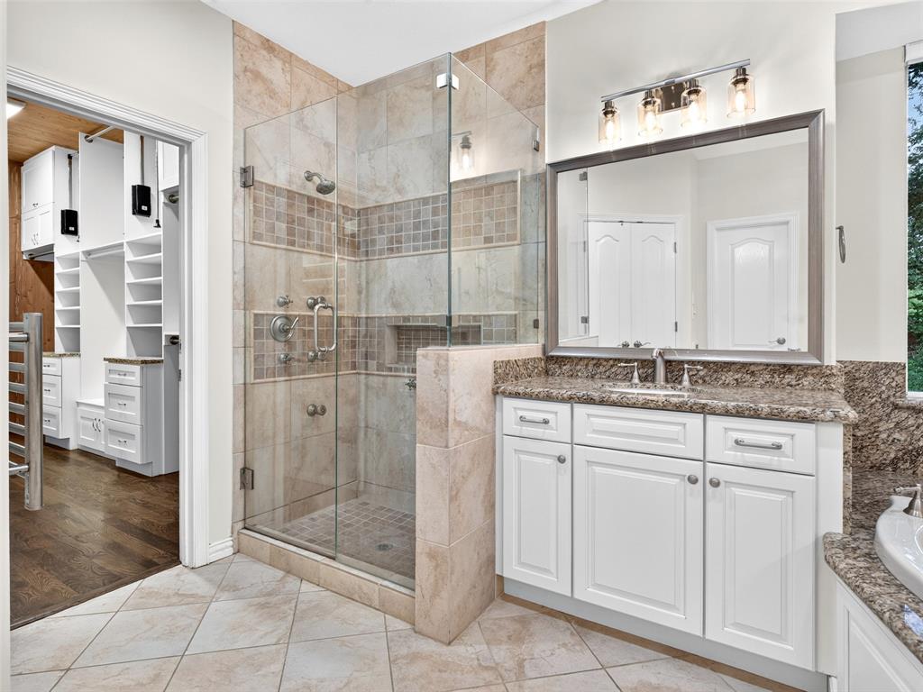 6809 Cedar Ridge Court Plano, TX 75093 - Photo 23 of 38 Walk-in shower with glass enclosure, single vanity with white cabinetry, polished chrome fixtures, and tile flooring