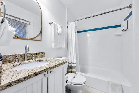 a bathroom with a granite countertop sink a mirror and shower