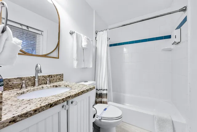 a bathroom with a granite countertop sink a mirror and shower