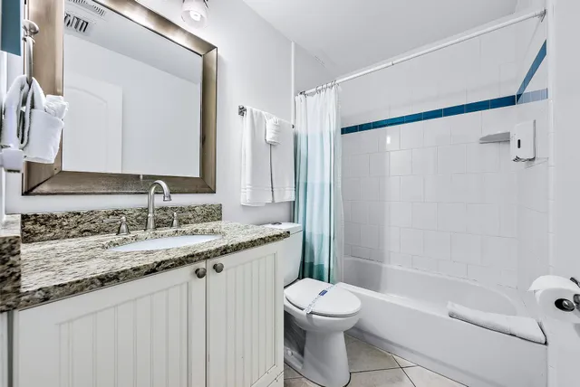 a bathroom with a granite countertop sink a toilet and shower