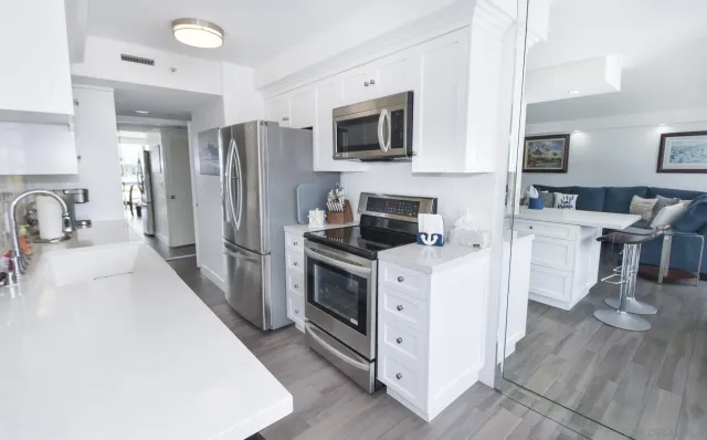 a kitchen with stainless steel appliances a stove top oven a sink a refrigerator white cabinets and wooden floor