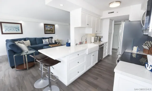 a large white kitchen with stainless steel appliances kitchen island granite countertop a table chairs and a refrigerator