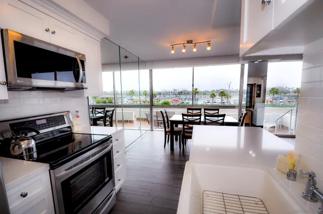 a kitchen with a stove a microwave a dining table and chairs with the view of living room