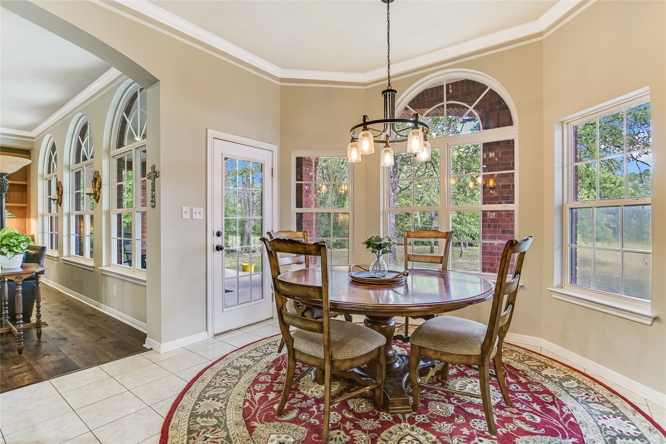 741 Knobbs Road McDade, TX 78650 - Photo 13 of 38 A well-lit breakfast area with an elegant chandelier and tall windows offers serene views of the surrounding natural landscape.