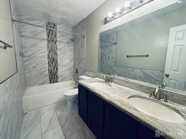 a bathroom with a granite countertop sink toilet mirror and bathtub