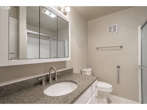 a bathroom with a granite countertop toilet sink and mirror