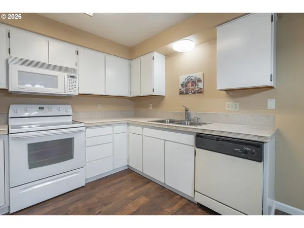 a kitchen with granite countertop white cabinets and white appliances