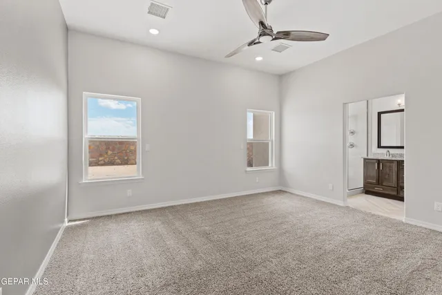 an empty room with windows and a ceiling fan