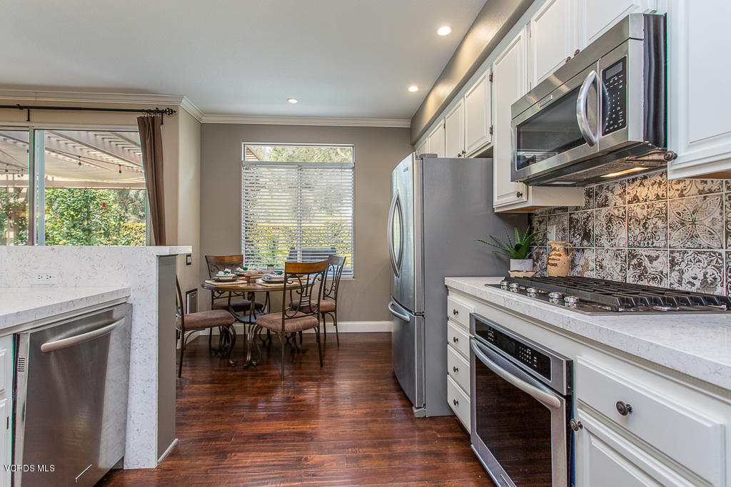 11249 Shadyridge Road Moorpark, CA 93021 - Photo 16 of 48 a kitchen with stainless steel appliances granite countertop a stove top oven a sink dishwasher a dining table and chairs with wooden floor