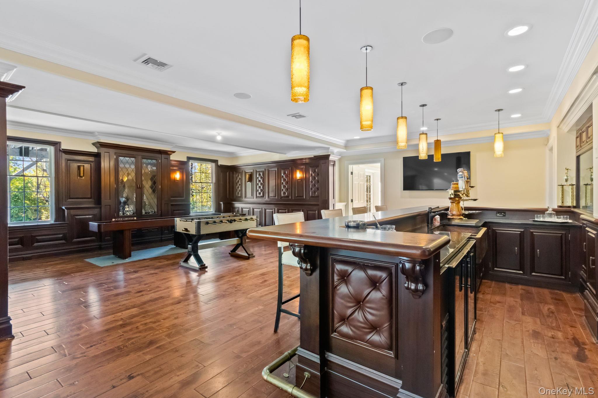 496 Long Ridge Road Bedford, NY 10576 - Photo 37 of 49 Kitchen featuring dark countertops, crown molding, a kitchen breakfast bar, decorative light fixtures, and dark brown cabinets
