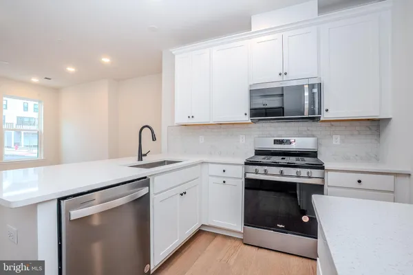 a kitchen with stainless steel appliances granite countertop a stove a sink and a microwave