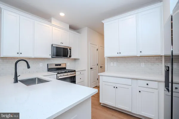 a view of a sink a microwave and cabinets