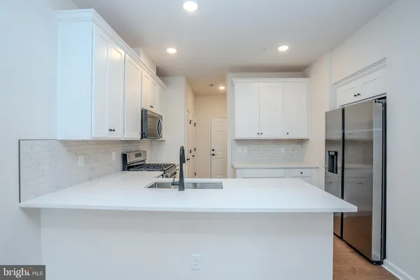 a kitchen with a sink a refrigerator and white cabinets