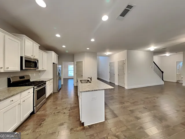 a large kitchen with stainless steel appliances kitchen island a large counter top and a stove top oven