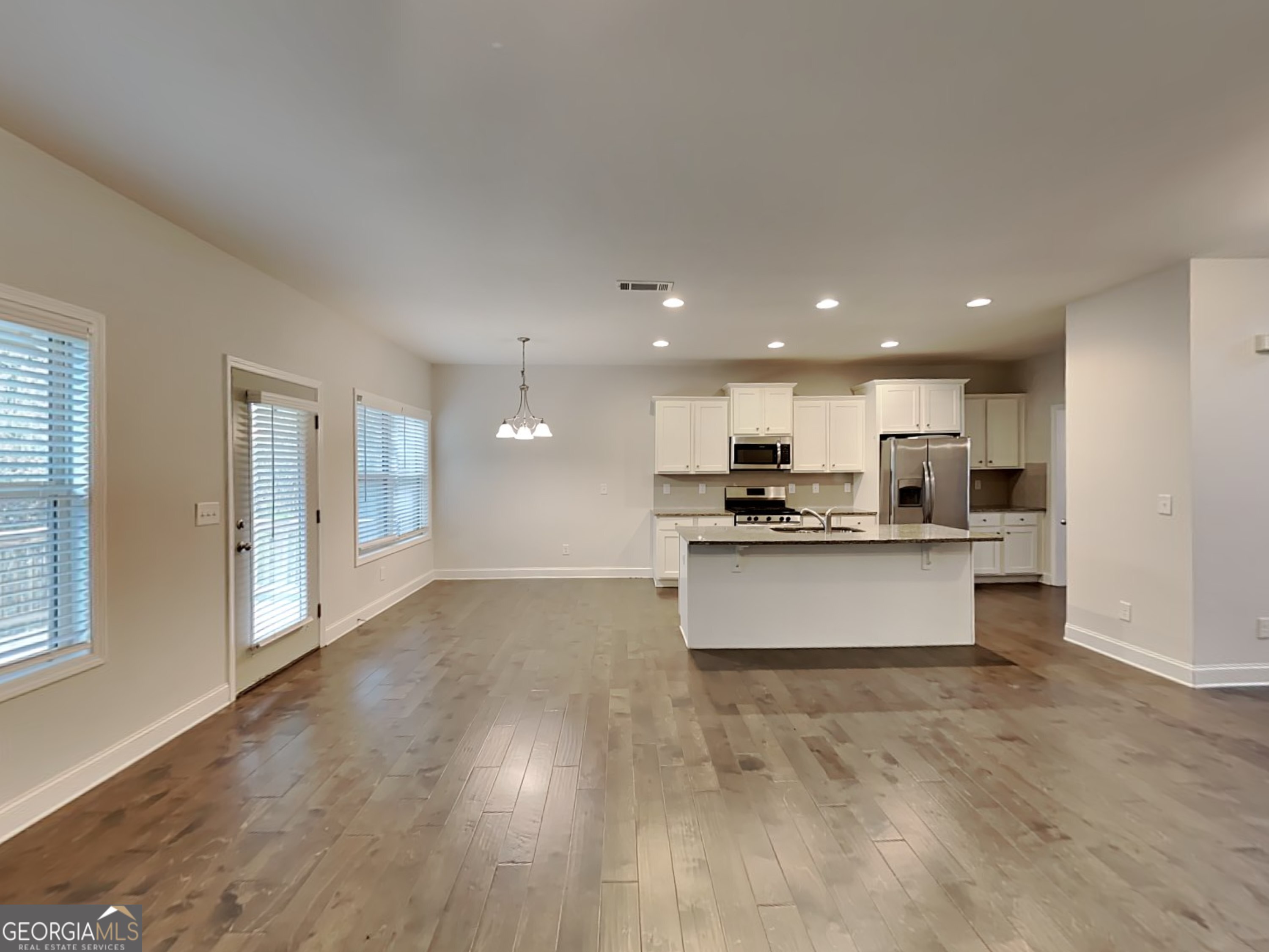 1781 Cobblefield Circle Dacula, GA 30019 - Photo 6 of 27 a large kitchen with kitchen island a stove a sink a refrigerator and white cabinets with wooden floor