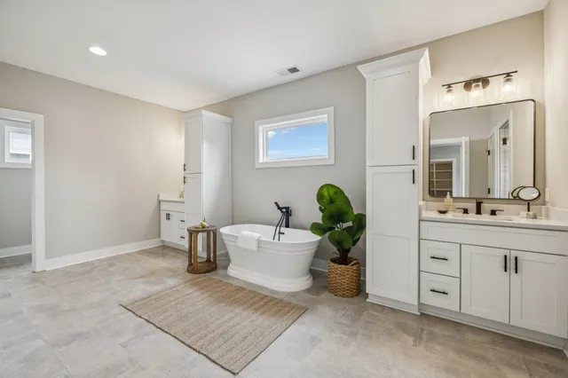 a spacious bathroom with a double vanity sink a mirror and a bathtub