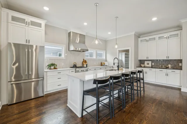 a kitchen with stainless steel appliances granite countertop a dining table chairs refrigerator and microwave