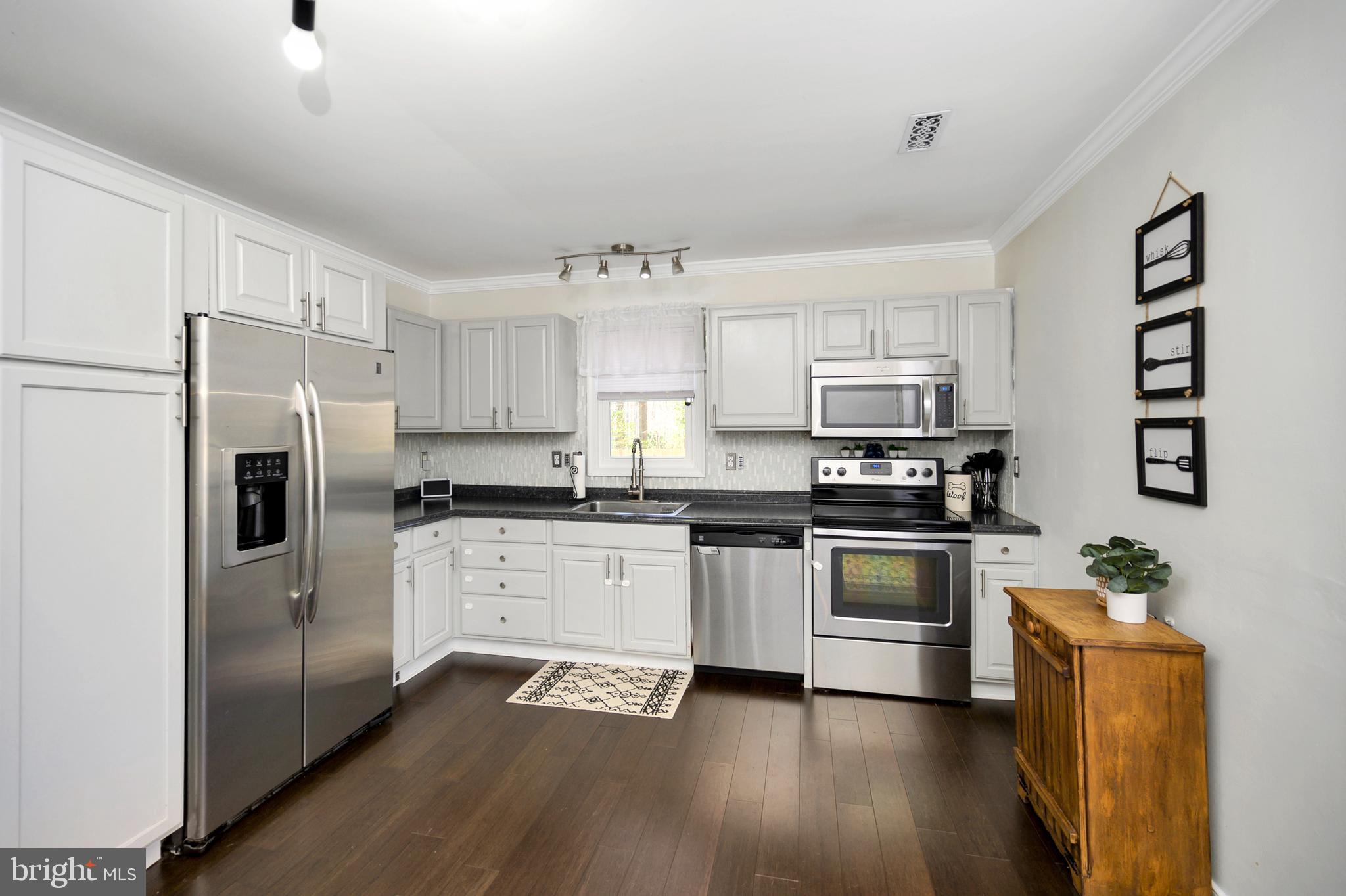 28 Benner Loop Ruther Glen, VA 22546 - Photo 26 of 54 a kitchen with granite countertop stainless steel appliances a sink a refrigerator a stove a microwave and cabinets