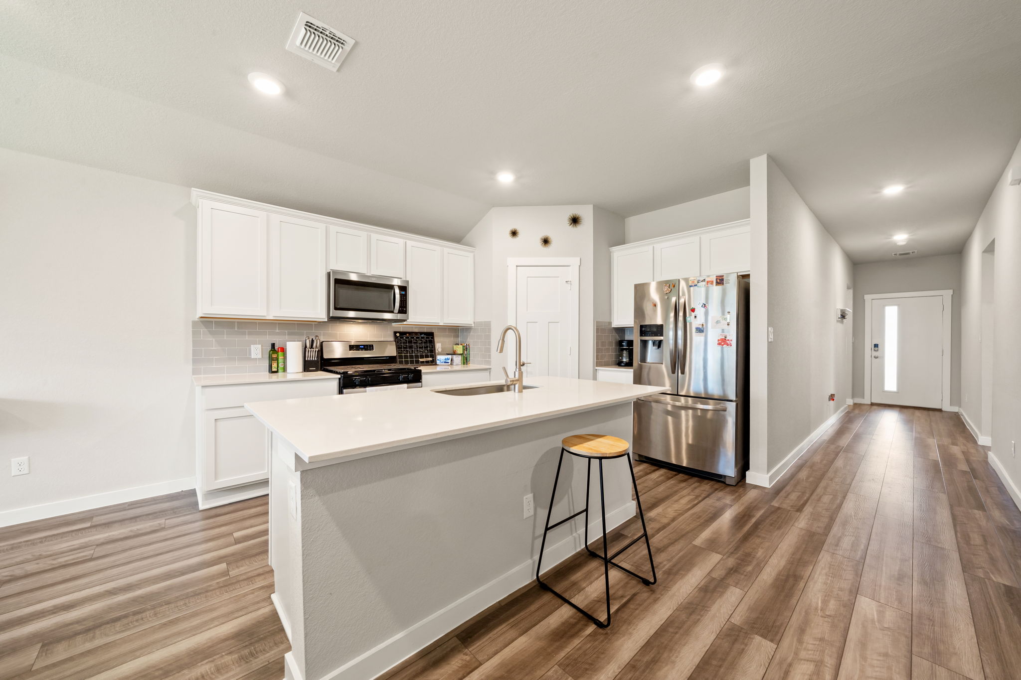 1117 Tipton Street Georgetown, TX 78633 - Photo 4 of 40 Contemporary kitchen featuring white cabinetry, stainless steel appliances, a center island with sink, and wood-finish flooring