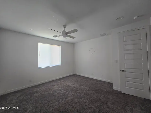 an empty room with a ceiling fan and window