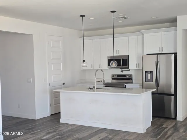 a kitchen with stainless steel appliances granite countertop a refrigerator a sink a stove and white cabinets