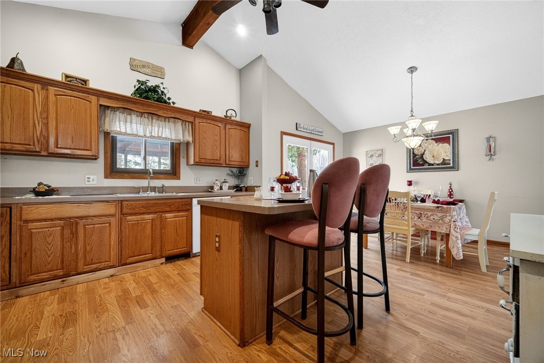 6379 Cary Road North Ridgeville, OH 44039 - Photo 8 of 29 Kitchen with a kitchen bar, a kitchen island, brown cabinetry, a chandelier, and light wood finished floors