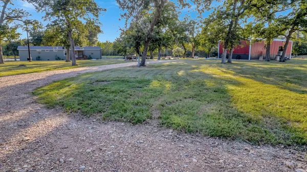a view of a house with a big yard and large trees