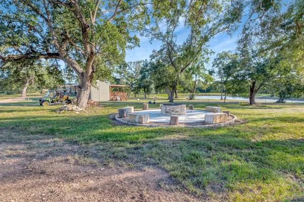 a view of a fountain in the yard with large trees