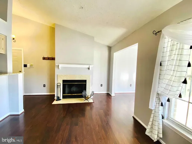 an empty room with wooden floor fireplace and windows