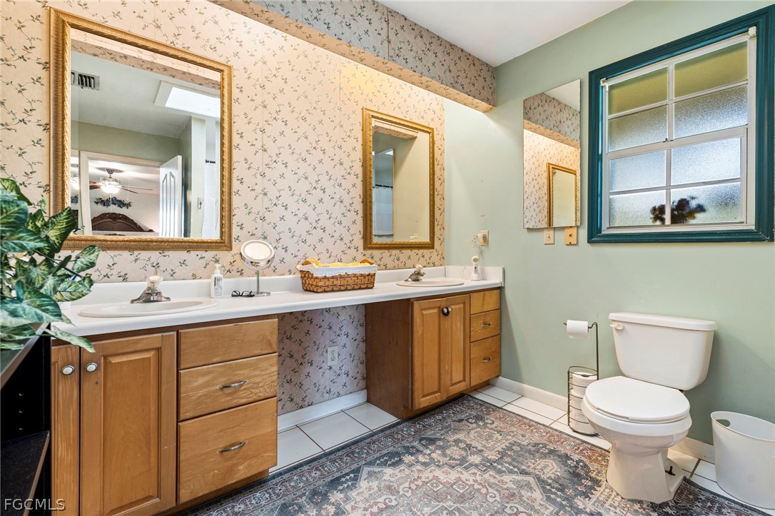 2724 3rd Street Southwest Lehigh Acres, FL 33976 - Photo 18 of 26 a bathroom with a toilet a sink a mirror and a window