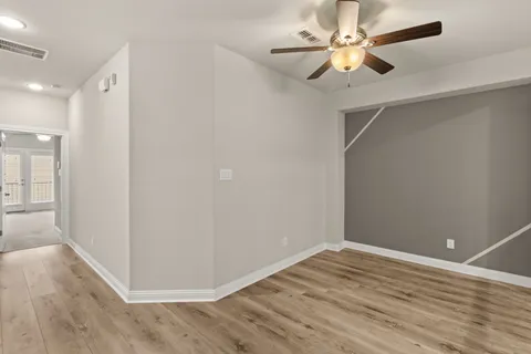 a view of a room with wooden floor and a ceiling fan