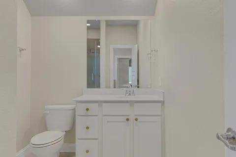 a bathroom with a granite countertop toilet a sink and a mirror