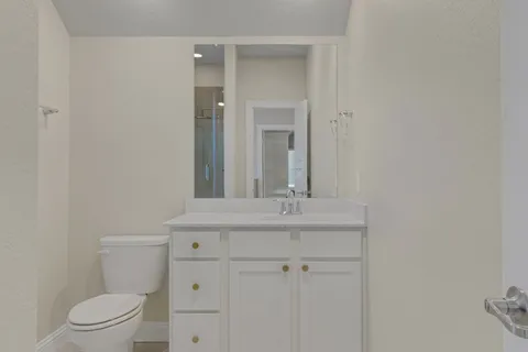a bathroom with a granite countertop toilet a sink and a mirror