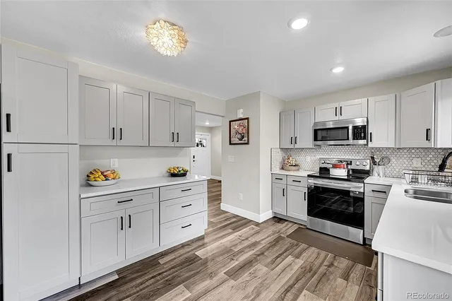 a kitchen with granite countertop white cabinets and stainless steel appliances