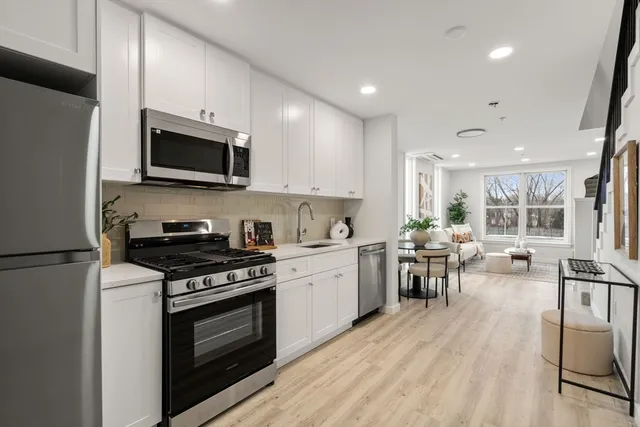 a kitchen with granite countertop a stove top oven a sink dishwasher a refrigerator and white cabinets with wooden floor