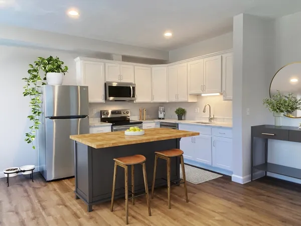 a kitchen with stainless steel appliances granite countertop a refrigerator a stove a sink a microwave a dining table and chairs with wooden floor