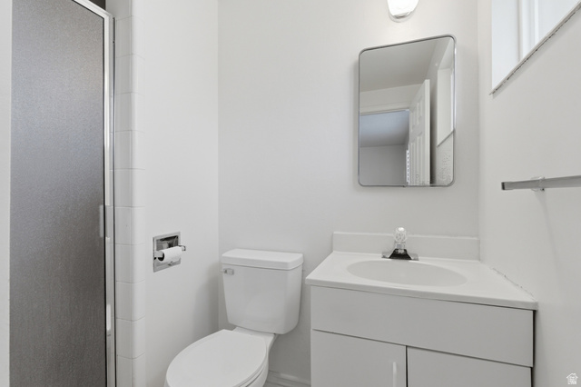 148 Tennyson Avenue Sandy, UT 84070 - Photo 22 of 55 Compact bathroom featuring a shower with a frosted glass door, a toilet, a vanity with an integrated sink, a wall-mounted mirror, and a chrome towel bar