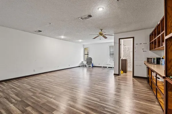 a view of empty room with wooden floor and a window