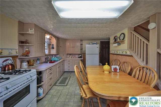 a kitchen with granite countertop a sink a stove a dining table and chairs